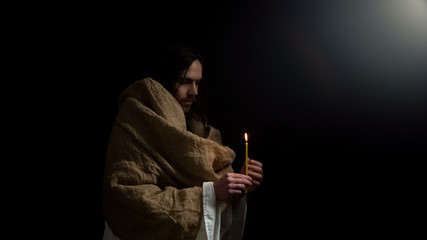 Christian holding candle in darkness, Jesus praying for souls of people, Easter