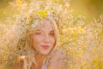 beautiful happy young lady in a wreath of summer flowers on nature