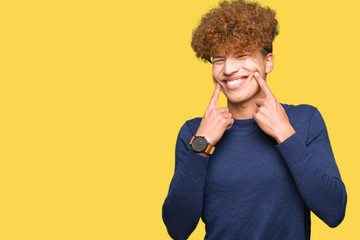 Young handsome man with afro hair Smiling with open mouth, fingers pointing and forcing cheerful smile