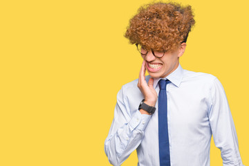Fototapeta na wymiar Young handsome business man with afro wearing glasses touching mouth with hand with painful expression because of toothache or dental illness on teeth. Dentist concept.