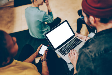 Cropped image of man sending multimedia content from his laptop computer to friend's smartphone via...