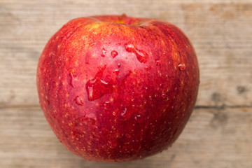 red apple on a wooden gray board, drops of water on the apple, texture, background, close-up, fruit