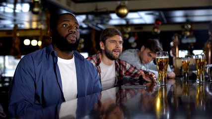 Deeply upset multiethnic fans watching championship in pub, team losing game