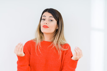 Young woman wearing casual red sweater over isolated background Doing money gesture with hand,...