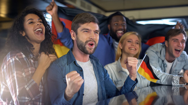 Enthusiastic german sports fans holding flag, happy about national team victory