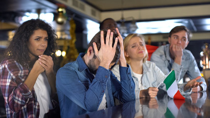 Sad Italian multiracial sport fans with flag disappointed about defeat in match