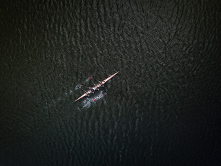 Aerial drone shot af academic rowing team in canoe on dark river