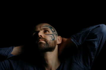 tattoo on the face,  male portrait in the form of an assassin, cosplay,  tattooed brutal man,  guy with a tattooed face