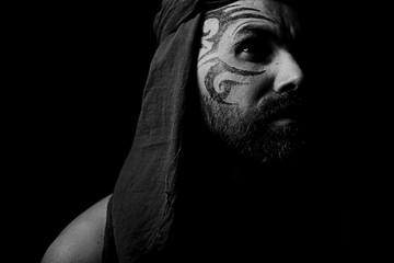 Fototapeta na wymiar tattoo on the face, male portrait in the form of an assassin, cosplay, tattooed brutal man, guy with a tattooed face
