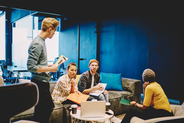 Skilled crew of multiracial employees brainstorming on informal meeting in coworking office share...