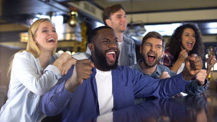 Black man with friends supporting sport team, rejoicing winning goal, victory
