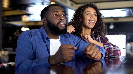 Obraz premium Multi-racial couple rooting for national team watching game, entertainment