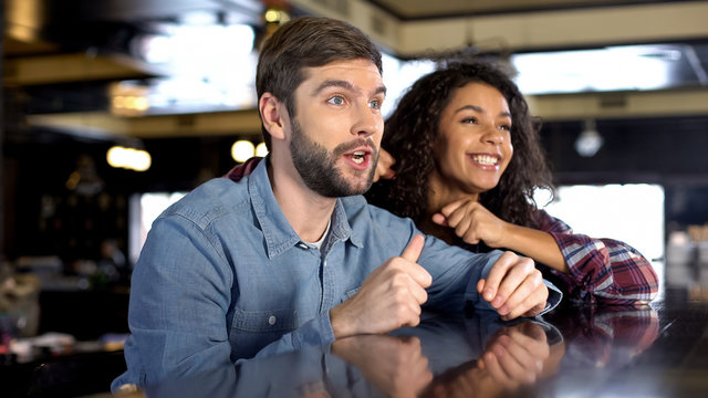 Male and female fans celebrating team victory, watching sport competition online