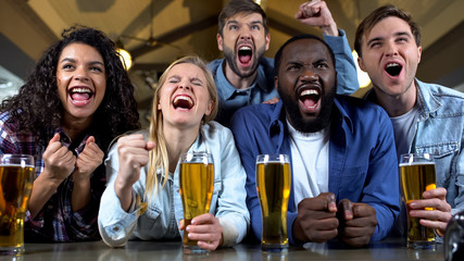 Young multi-racial friends rooting for favorite team, watching championship pub