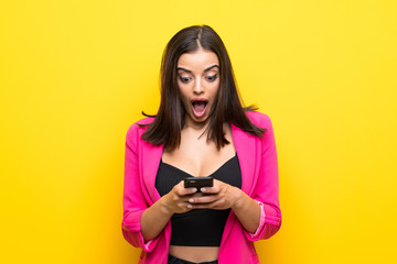 Fototapeta premium Young woman over isolated yellow background surprised and sending a message