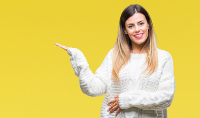 Young beautiful woman casual white sweater over isolated background smiling cheerful presenting and pointing with palm of hand looking at the camera.
