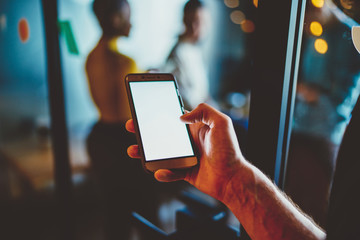 Cropped view of hand holding smartphone device with copy space area for your internet content.Selective focus on finger typing on display of modern mobile phone with mock up area for advertising text