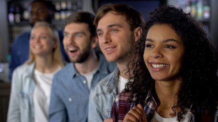 Smiling mixed-race friends rooting for team, watching contest, event audience