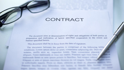Contract lying on table, pen and eyeglasses on official document, business