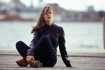 girl in a leather jacket sits outside the rustic style