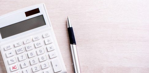 White calculator and pen on bright wooden table, analytics and statistics of financial profit, investment risk concept, copy space, top view flat lay