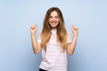 Fototapeta premium Young woman over isolated blue background celebrating a victory in winner position