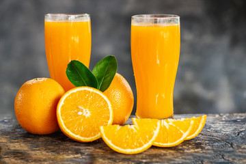 orange sliced and orange juice glasses with green leaf on wooden table 
