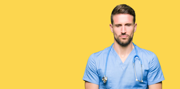 Handsome doctor man wearing medical uniform over isolated background depressed and worry for distress, crying angry and afraid. Sad expression.