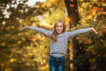 beautiful girl throws leaves in  autumn forest