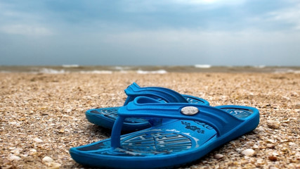Blue beach shoes by the sea. Against the blue sky