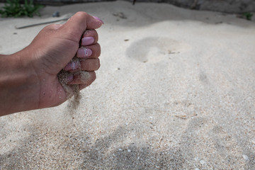 Cut out women's hands, sand pours through fingers.