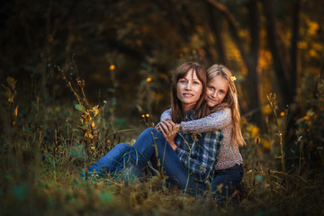 beautiful woman with her daughter in the fall in a beautiful forest