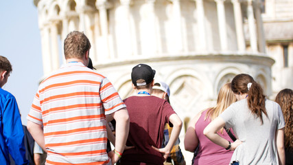 Crowd of people stay under the leaning tower of Pisa