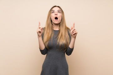 Young woman over isolated background surprised and pointing up