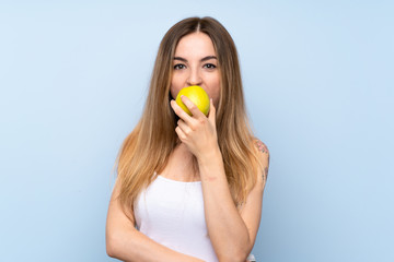 Young woman over isolated blue background with an apple