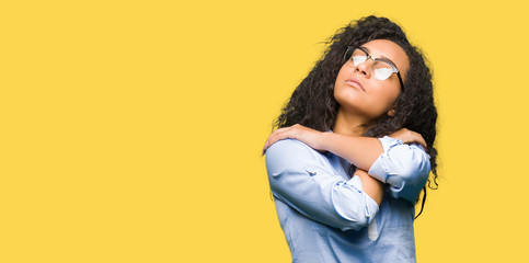 Young beautiful business girl with curly hair wearing glasses Hugging oneself happy and positive, smiling confident. Self love and self care