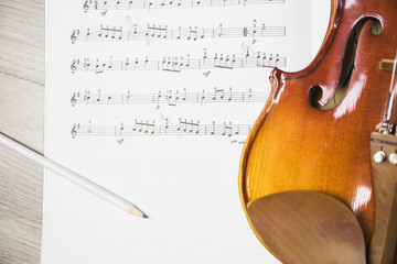 Pencil and violin over the musical note on table