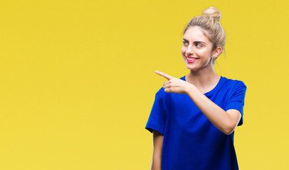 Young beautiful blonde and blue eyes woman wearing blue t-shirt over isolated background cheerful with a smile of face pointing with hand and finger up to the side with happy and natural expression
