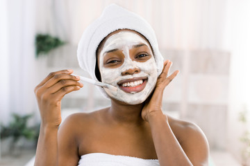 vitamin facial mask. African smiling woman with a face in a mask in spa