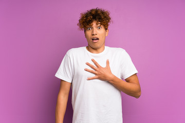 Young african american man over isolated purple wall surprised and shocked while looking right