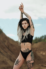Beautiful sexy woman in black underwear. The body is covered with many tattoos. Dreadlocks on the...