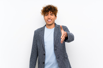 Fashion african american man over isolated white wall shaking hands for closing a good deal