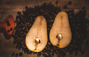 Pera en un fondo de madera  y rodeada por granos de café