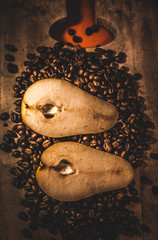 Pera en un fondo de madera  y rodeada por granos de café