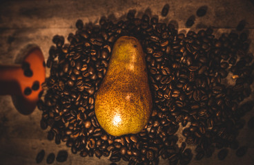 Pera en un fondo de madera  y rodeada por granos de café