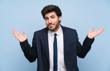 Businessman over isolated blue wall making doubts gesture