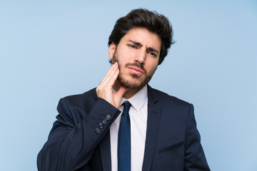 Businessman over isolated blue wall with toothache