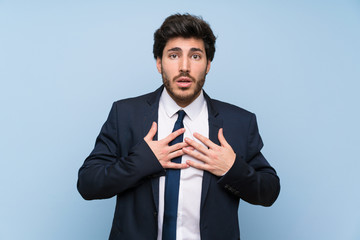 Businessman over isolated blue wall surprised and shocked while looking right