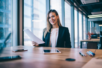 Portrait of successful caucasian female entrepreneur sitting at desktop with paper documents and...