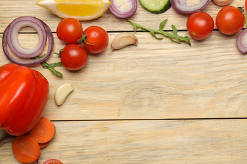 Ingredients for cooking salad. frame of Various vegetables and spices carrot, tomato, onion, cucumber, pepper and arugula on a natural wooden table. top view.